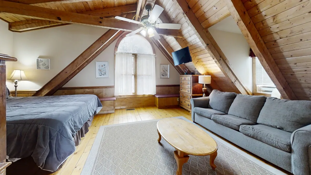 A warm, welcoming seating area highlighted by timber beams, a panoramic window, and comfortable chairs arranged for easy conversation or relaxation. The natural light pouring in creates a space ideal for informal meetings, team discussions, or simply soaking in mountain views over coffee.